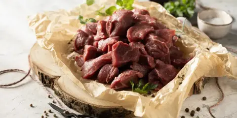 Pokrojone w kostkę mięso na gulasz z dzika, ułożone na papierze, gotowe do przyrządzenia.