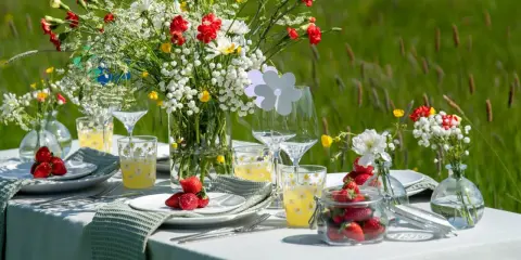 Vackert dukat bord med blommor och jordgubbar för att duka till midsommar.