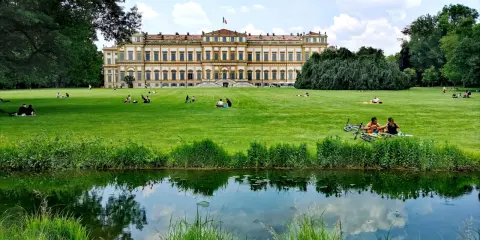 Villa Reale di Monza e il suo parco: un'idea per cosa vedere a Monza in un giorno. Persone rilassate sull'erba, un laghetto e il maestoso edificio.