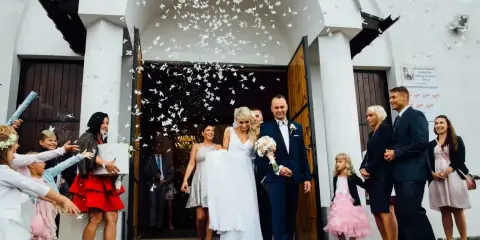 Para młoda wychodzi z kościoła, obsypana płatkami. Piękny moment z polskich wesel.