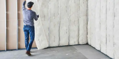Hombre instala aislamiento en pared ya construida. Proceso de como aislar una pared.