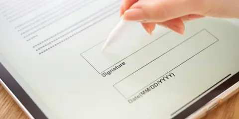 Mano firmando un contrato de arrendamiento digitalmente en una tableta con un lápiz óptico.