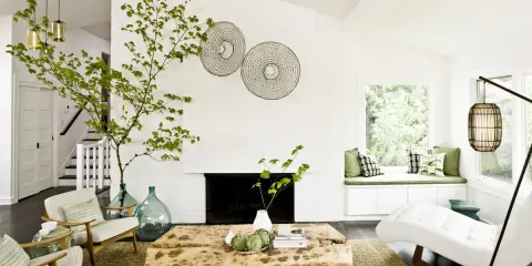 Ideas para decorar ramas secas: una rama verde decora el salón moderno con chimenea, mesa de madera y sillones.