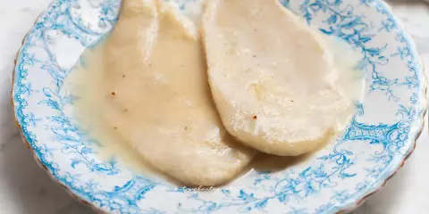 Due scaloppine al vino bianco, tenere e succulente, servite su un piatto decorato con motivi blu.