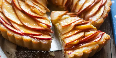 Una fetta di crostata di mele dorata, con mele caramellate disposte a rosa su una base friabile.