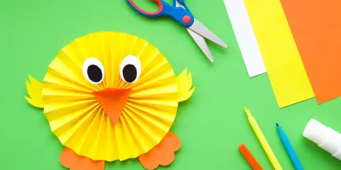 Manualidades para niña de 2 años: un pollito de papel. Tijeras, papeles de colores, rotuladores y pegamento listos para crear.