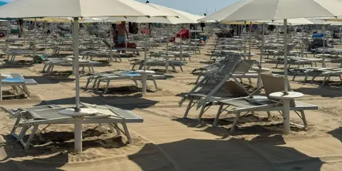 Ombrelloni e lettini pronti per il Ferragosto sulla Riviera Romagnola. La sabbia dorata attende i bagnanti.