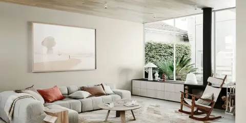 Salón moderno con sofá modular gris, alfombra abstracta y arte de playa. Muestra todos los estilos de decoración de interiores.