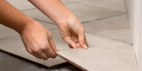 Manos colocando una baldosa de porcelánico para cortar a medida.