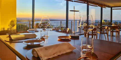 Tavola apparecchiata in un ristorante stellato a Gabicce Monte, con vista sul tramonto sul mare.