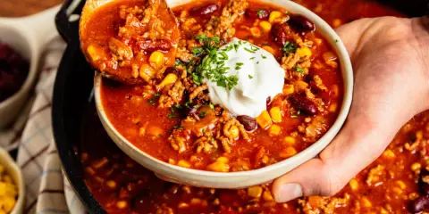 Herzhaftes Chili con Carne aus dem Dutch Oven, serviert mit einem Klecks Sour Cream und frischer Petersilie.