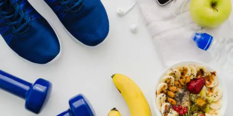 Gesunde Ernährung vor dem Halbmarathon: Haferflocken mit Früchten, Bananen, Apfel, Wasser und Sportutensilien.