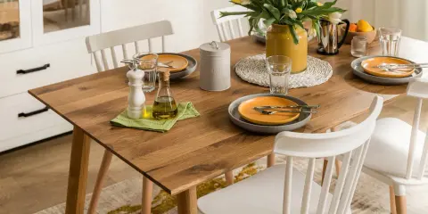 Elegancka, codzienna dekoracja stołu w salonie: drewniany blat, żółte tulipany, oliwa i przyprawy.