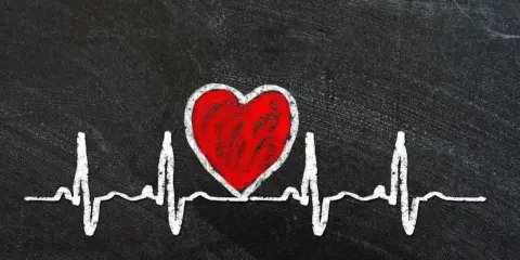 Czerwone serce na tle EKG symbolizuje zagrożenia dla zdrowia serca, w tym skutki otyłości u mężczyzn.