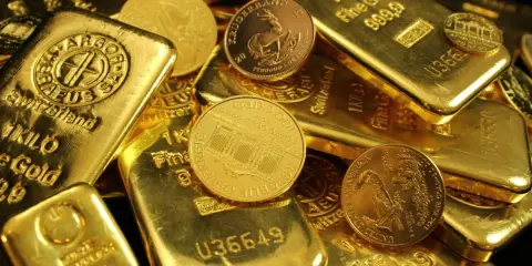 Złote sztabki i monety, niektóre z napisem "1 KILO Fine Gold".