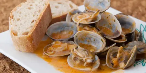 Almejas a la marinera, jugosas y sabrosas, servidas con pan rústico para mojar en la deliciosa salsa.