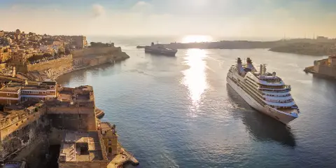 MSC Crociere: documenti di viaggio pronti per una crociera al tramonto tra fortezze storiche e navi maestose.