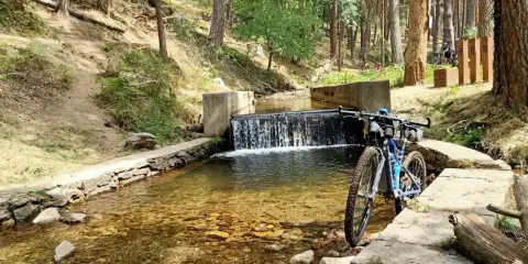 Bicicleta de montaña junto a una cascada en un arroyo, ideal para rutas por Segovia.