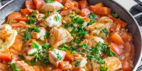Succulento pollo alla pizzaiola in padella, con pomodoro fresco e prezzemolo. Un piatto saporito e invitante.