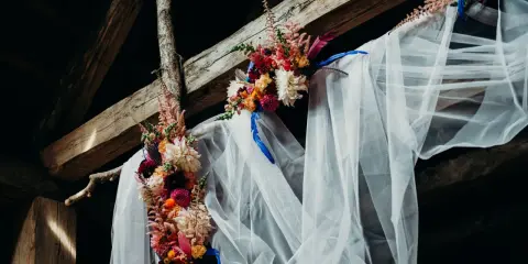 Blumenbogen mit Schleier unter Holzbalken, ein romantischer Ort für eine Feier, vielleicht zum 5 Jahre verheiratet Jubiläum.