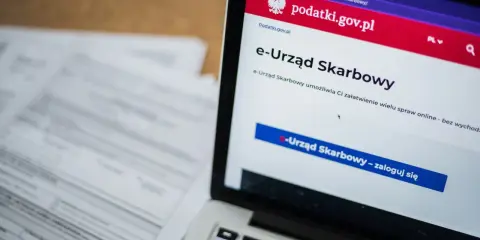 Na ekranie laptopa widoczny jest portal e-Urząd Skarbowy. Obok leżą dokumenty, które mogą zawierać identyfikator zobowiązania.