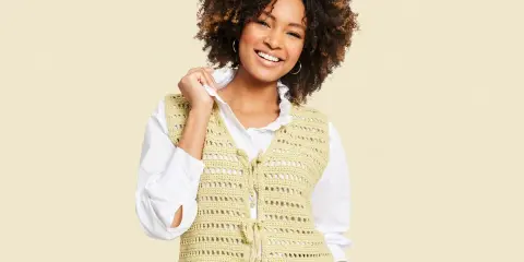 Mujer sonriente con chaleco de crochet con patrón calado, atado al frente.