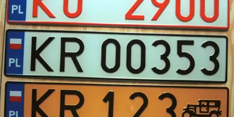 Kolekcja tablic rejestracyjnych świata: polskie tablice KO 2900, KR 00353 i KR 123 z zabytkowym autem.