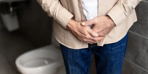 Mężczyzna trzyma się za podbrzusze, zastanawiając się, jakie badania na prostate są najlepsze.