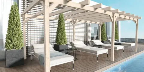 Une **pergola bois** avec des canisses protège des chaises longues au bord d'une piscine.