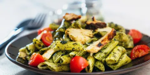 Penne z kurczakiem i pomidorkami, obficie polane aromatycznym makaronem z pesto bazyliowym. Pyszny obiad gotowy!