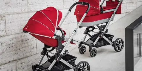 Dwa czerwone wózki dziecięce, eleganckie i stylowe, od renomowanego producenta wózków dziecięcych.