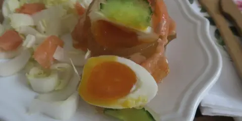 Un œuf en gelée au saumon, garni de concombre et servi avec des dés de saumon fumé et des endives. Un délice !