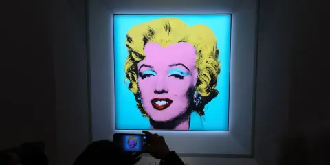 A person photographs Andy Warhol's iconic Marilyn Monroe printmaking, capturing the vibrant colors and pop art style.