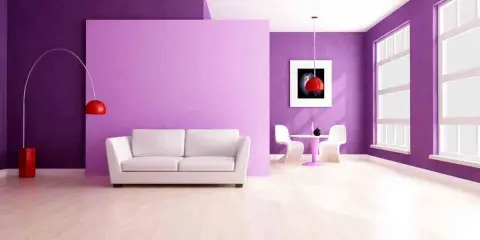 Sala moderna con paredes en **lila color** y morado, sofá blanco, mesa y sillas, y un suelo de madera clara.