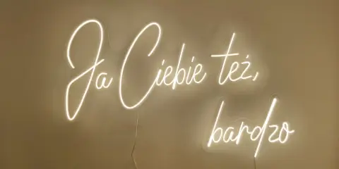 Neonowy napis "Ja ciebie też bardzo" rozświetla ścianę, tworząc ciepłą atmosferę.