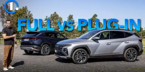 Uomo indica due SUV, uno blu e uno grigio, con la scritta "FULL VS PLUG-IN". Quando una auto ibrida non conviene.