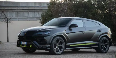Un imponente **lamborghini urus negro** se exhibe con detalles en verde lima, posado sobre un camino empedrado.