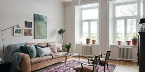 En vardagsrumsinredning som visar vad bohemisk betyder: en brun skinnsoffa, en stor mönstrad matta, konst och växter.