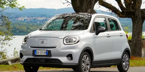 Leapmotor T03, un'auto elettrica grigia parcheggiata vicino a un lago, pronta per un viaggio con la sua eccellente autonomia.