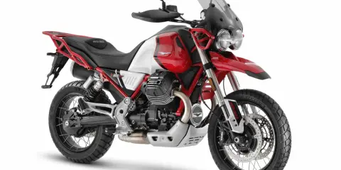 Czerwono-biały motocykl Moto Guzzi V85 TT z czarnym siedzeniem i akcentami, gotowy na przygodę.