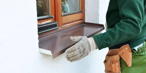 Instalación de un vierteaguas metálico en una ventana. El vierteaguas protege la pared de la lluvia.
