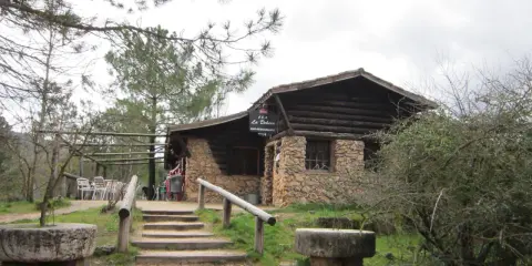 Mesones Riopar: acogedor bar-restaurante de piedra y madera en un entorno natural. Escaleras de acceso y mesas exteriores invitan a disfrutar.