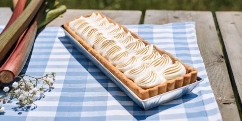 Tarte à la rhubarbe meringuée alsacienne, prête à être dégustée sur une nappe à carreaux bleus.