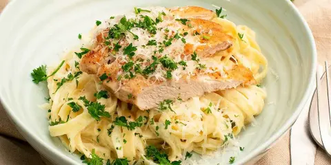 En krämig kyckling alfredo med tagliatelle, toppad med grillad kyckling, parmesan och färsk persilja. Ett perfekt recept för en snabb middag.
