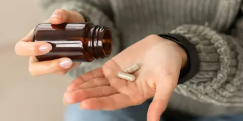 Dłoń z kapsułkami, które mogą wywołać biotyna skutki uboczne.