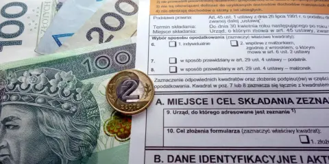 Polskie banknoty i monety na tle formularza podatkowego, ilustrujące ulga termomodernizacyjna – przykład rozliczenia.