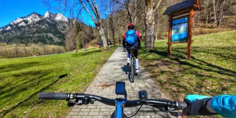 Rowerzyści przemierzają malowniczą ścieżkę rowerową w Szczawnicy, podziwiając górskie krajobrazy.