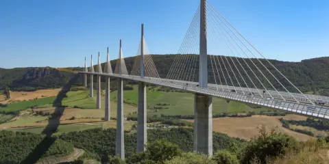 El viaducto de Millau, una maravilla de la ingeniería, se alza majestuoso sobre un valle verde. Su construcción desafía la gravedad.