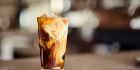Ein Glas Eiskaffee mit cremigen Wirbeln von Baileys, perfekt für einen entspannten Nachmittag.