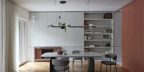 Sala da pranzo moderna con tavolo ovale, sedie imbottite e libreria a giorno. Le pareti grigio luminoso creano un'atmosfera sofisticata.